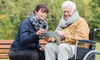 caregiver and elder man looking at the tablet