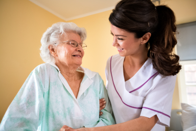 nurse helps senior woman to walk